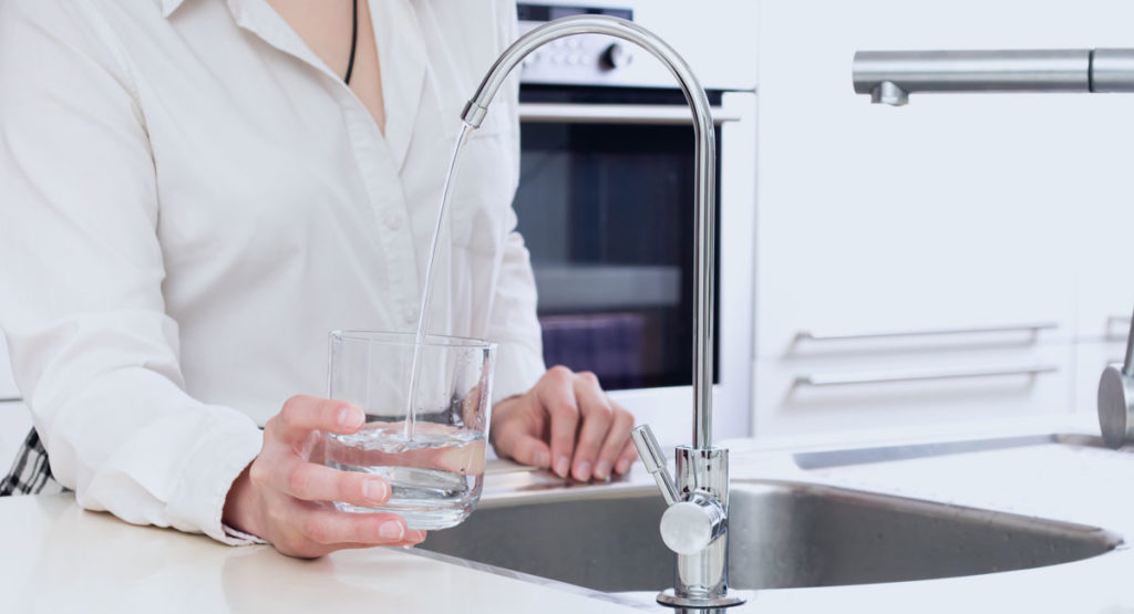 photo of woman using reverse osmosis tap